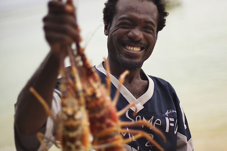 Local fisherman Kelford Joseph proudly presents todays catch, two impressive lobsters, at Pigeon Point, Tobago